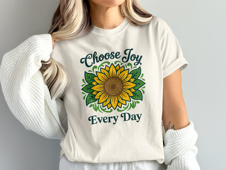 Off-white t-shirt with green text "Choose Joy Every Day" and a central sunflower graphic.