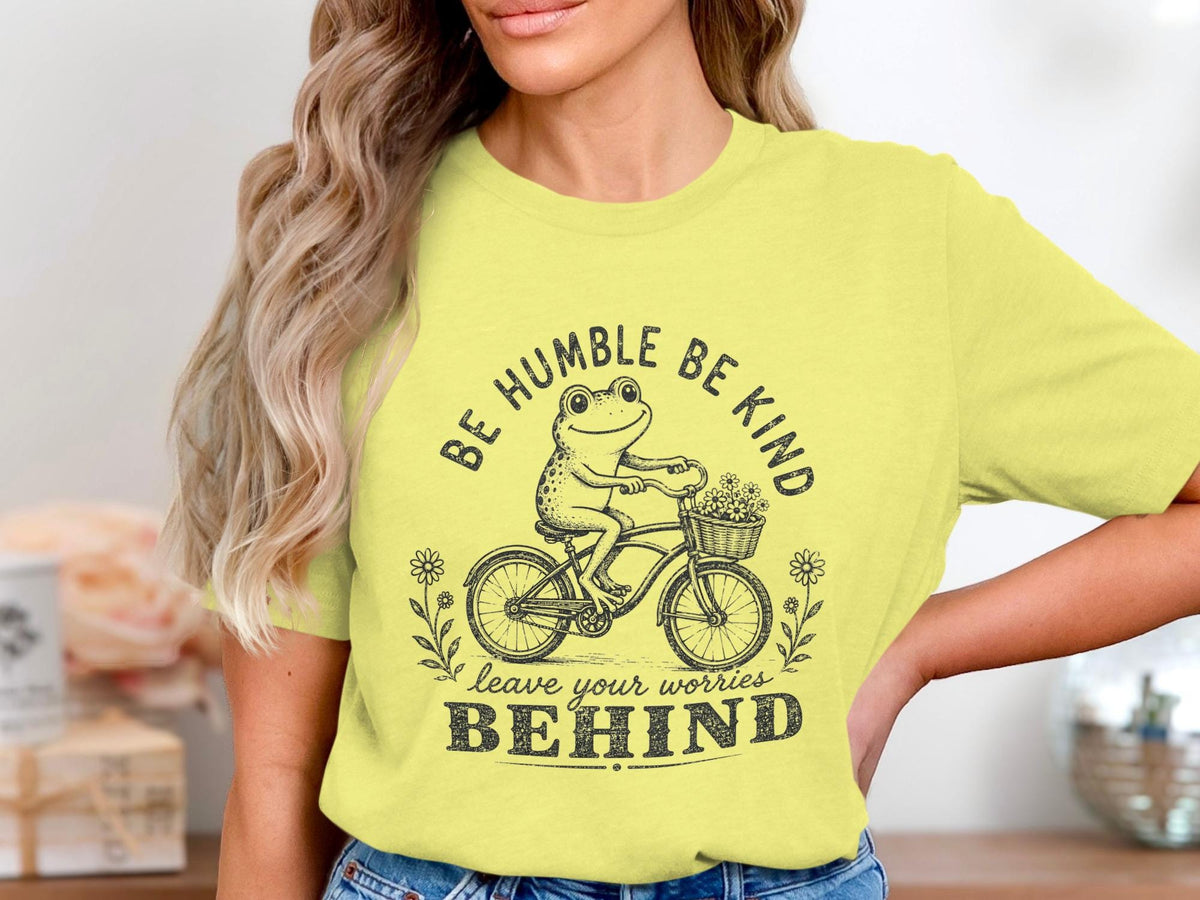Frog riding bicycle with flowers, text "BE HUMBLE BE KIND leave your worries BEHIND".