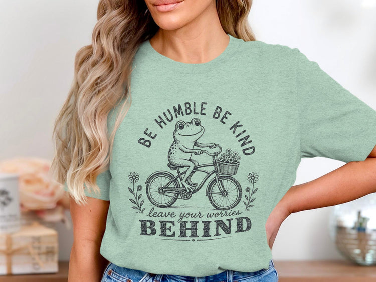 Frog on bicycle with flowers and text "BE HUMBLE BE KIND LEAVE YOUR WORRIES BEHIND."
