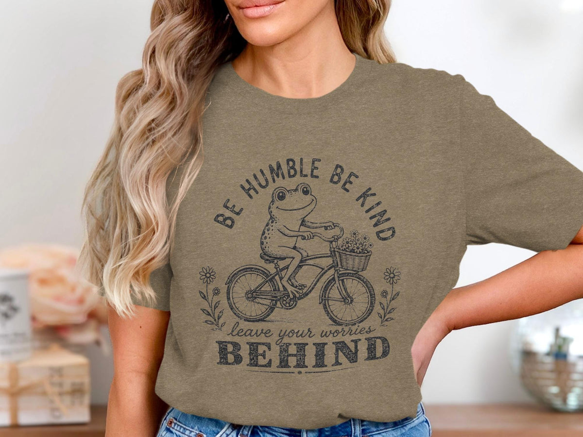 T-shirt graphic of frog on bicycle with text "Be Humble Be Kind leave your worries BEHIND".