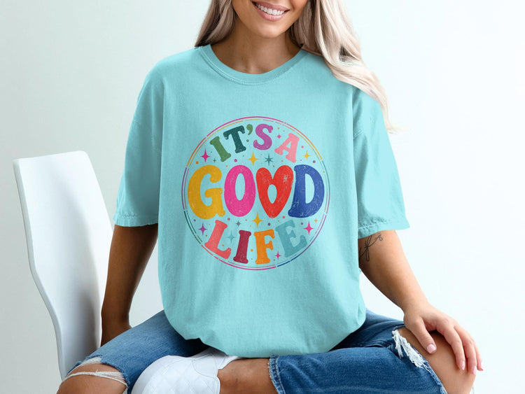 Teal t-shirt with "IT'S A GOOD LIFE" text in a colorful, retro circle design.