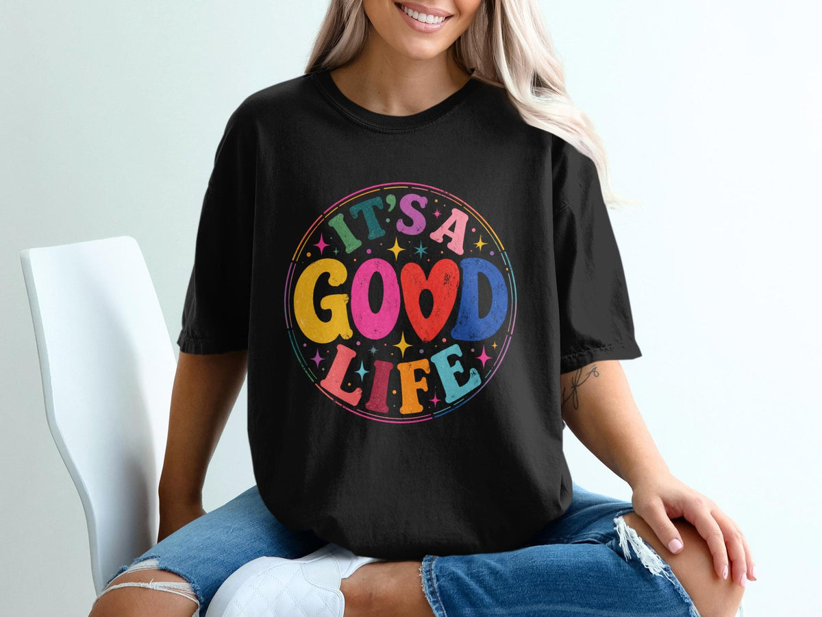Black t-shirt with colorful "It's a Good Life" graphic in a circular retro font.