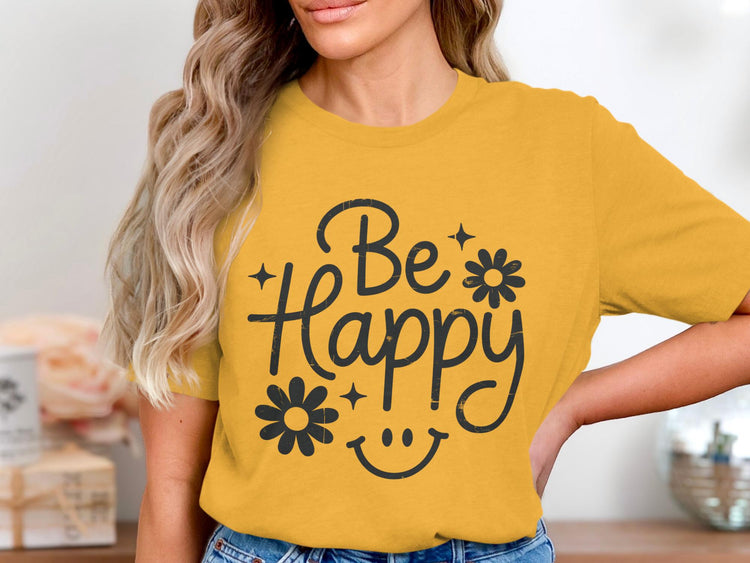 Yellow t-shirt with black "Be Happy" text, flowers, stars, and smiley face graphic.