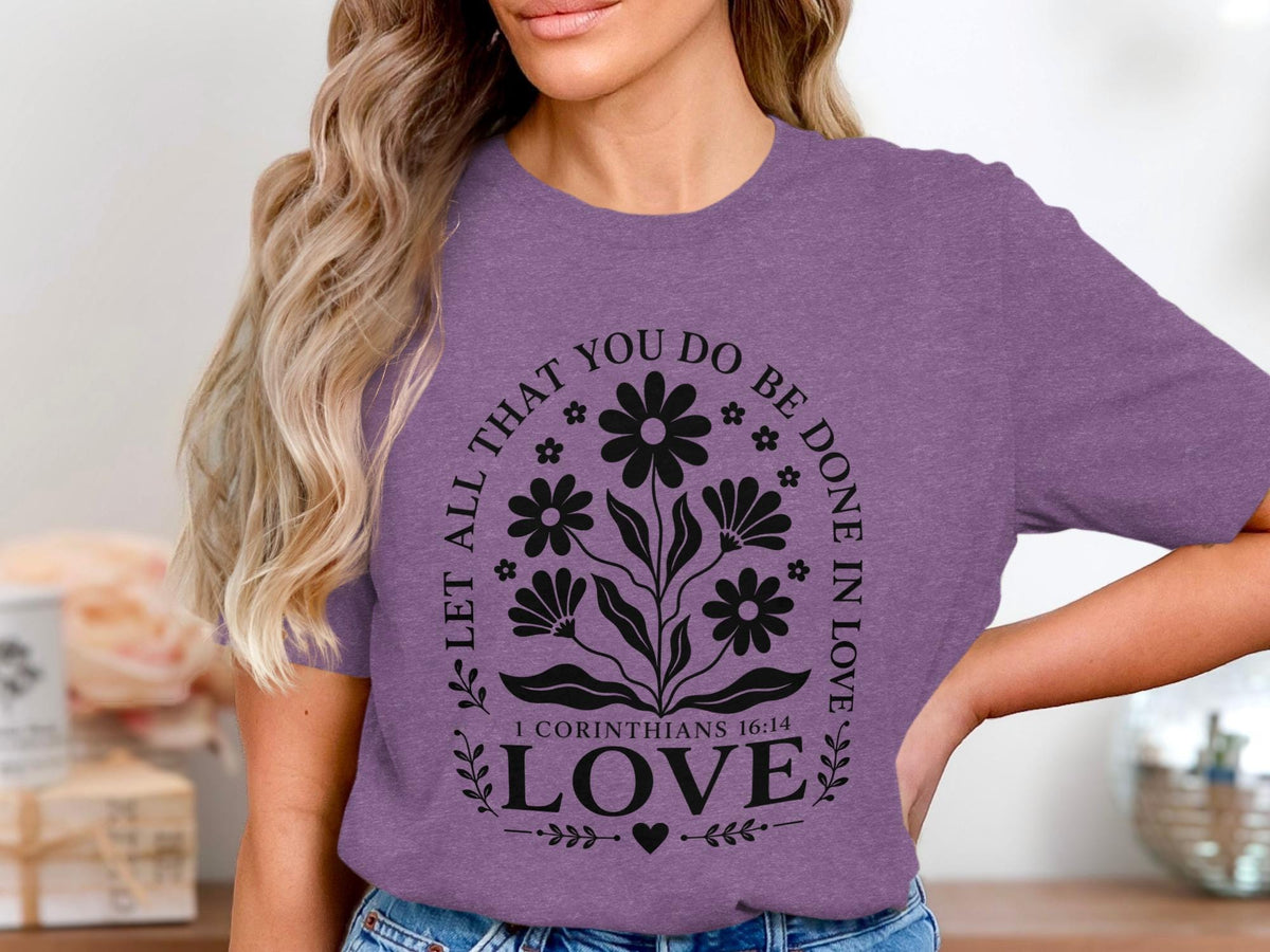 Purple t-shirt with black floral design and text "LET ALL THAT YOU DO BE DONE IN LOVE 1 CORINTHIANS 16:14 LOVE".