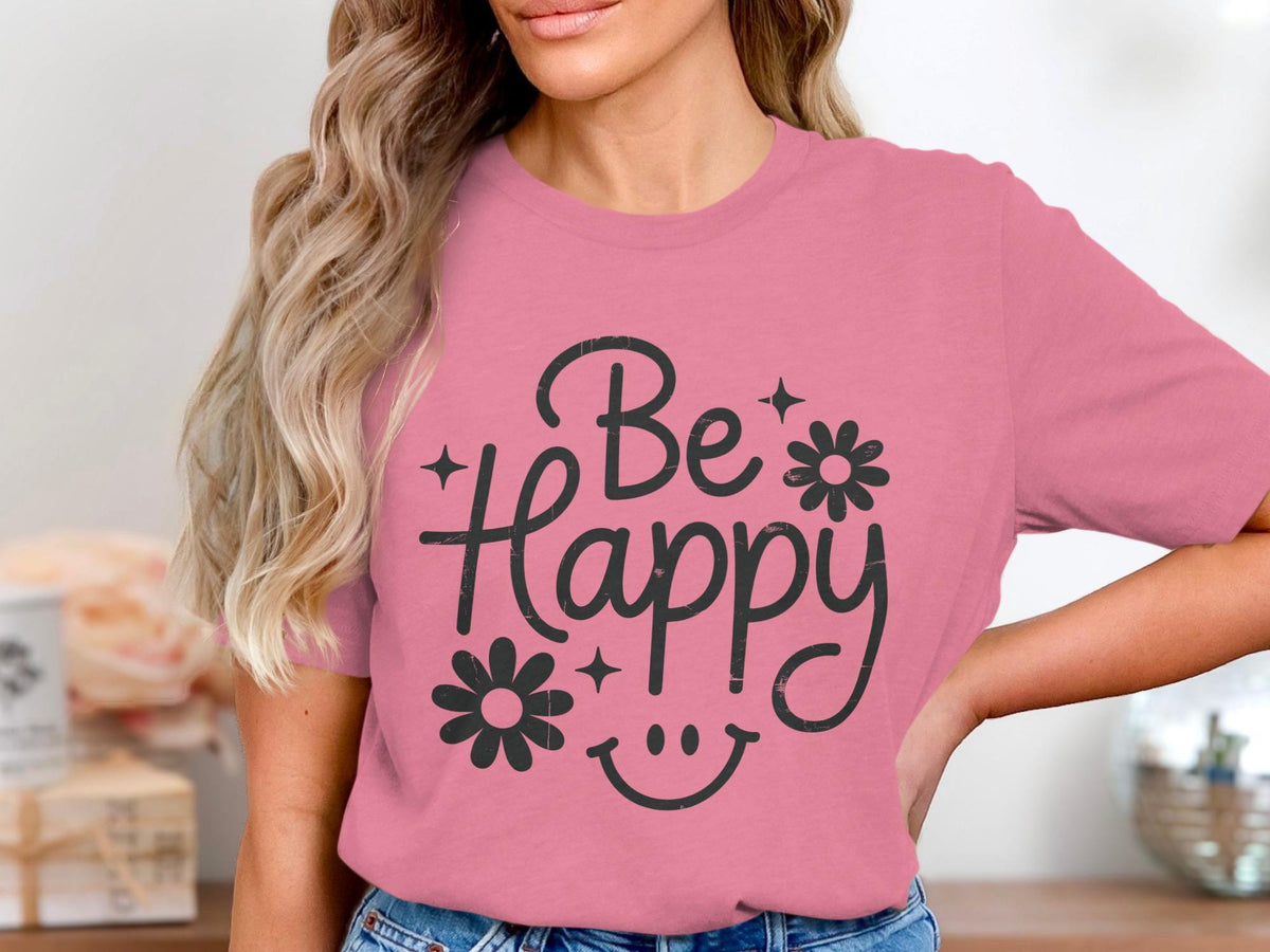 Pink t-shirt with "Be Happy" text, flowers, and smiley face graphic.