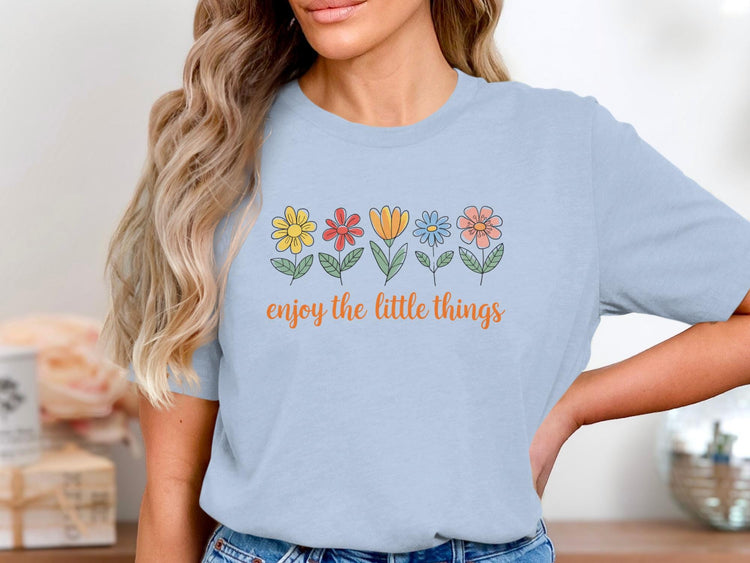 Light blue t-shirt with line art flowers and "enjoy the little things" text.