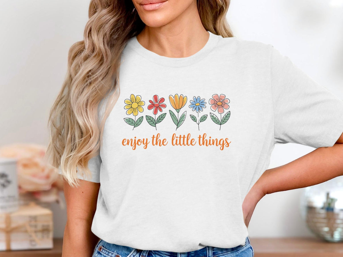 White t-shirt with colorful floral graphic and text "enjoy the little things."