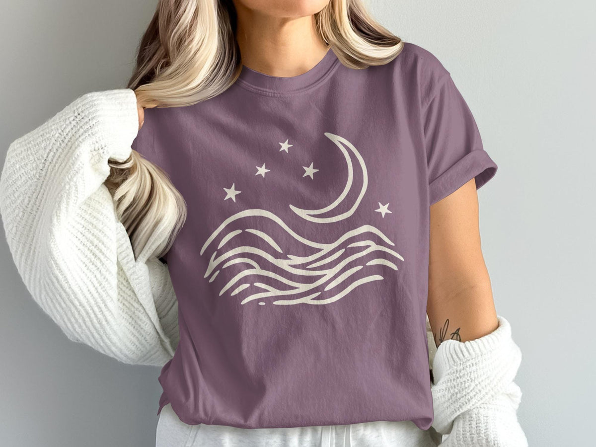 Purple t-shirt with cream moon, stars, and wavy lines graphic design.