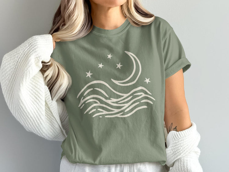 Sage green t-shirt with cream wave, moon, and star graphic.