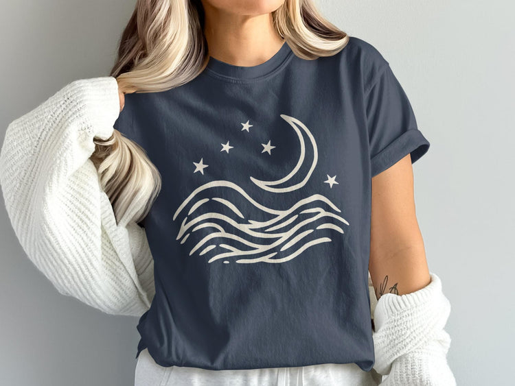 Dark blue t-shirt with cream colored moon, stars, and wave graphic.