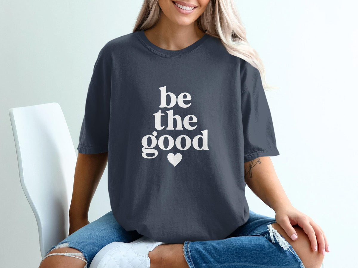 Dark gray t-shirt with white text "be the good" and a small heart.