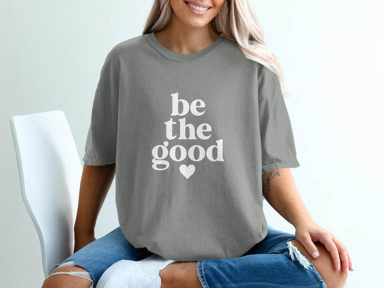 Grey t-shirt with white text "be the good" and a heart.