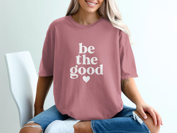 Pink t-shirt with white text "be the good" and a heart.