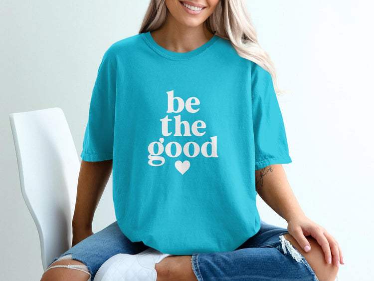 Teal t-shirt with white text "be the good" and a heart.
