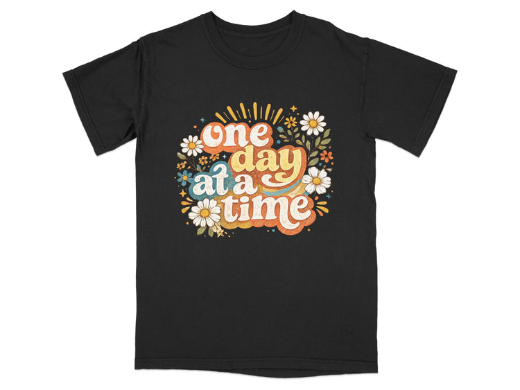 Black t-shirt with "one day at a time" text and floral design.
