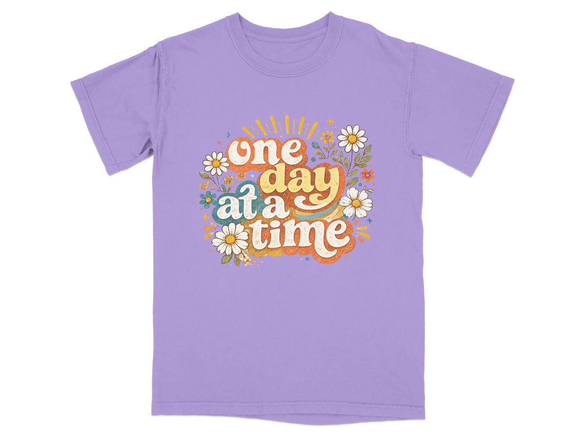 Purple t-shirt with "one day at a time" text surrounded by retro flowers.