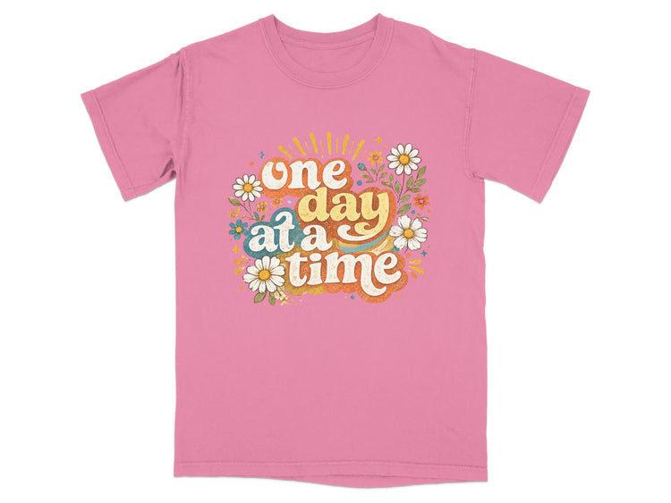 Pink t-shirt with "one day at a time" text and floral graphics
