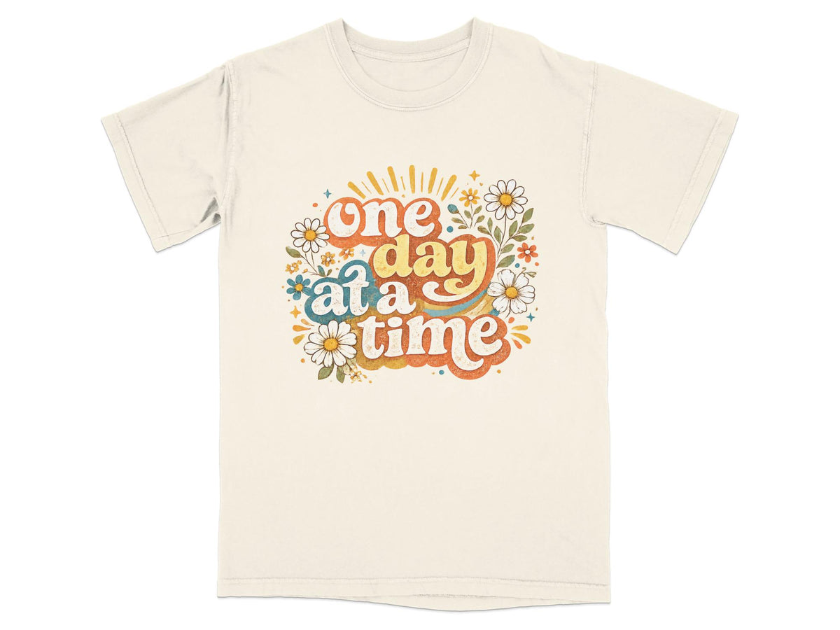 Cream t-shirt with groovy text "one day at a time" and floral graphics.