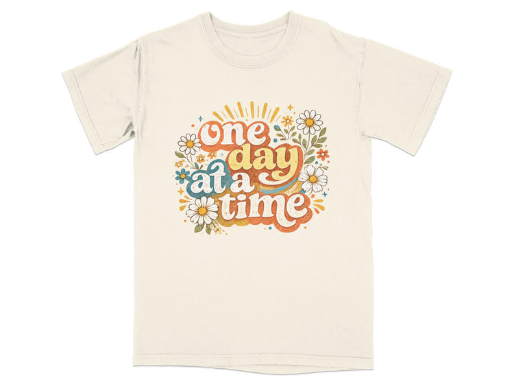 Cream t-shirt with groovy text "one day at a time" and floral graphics.