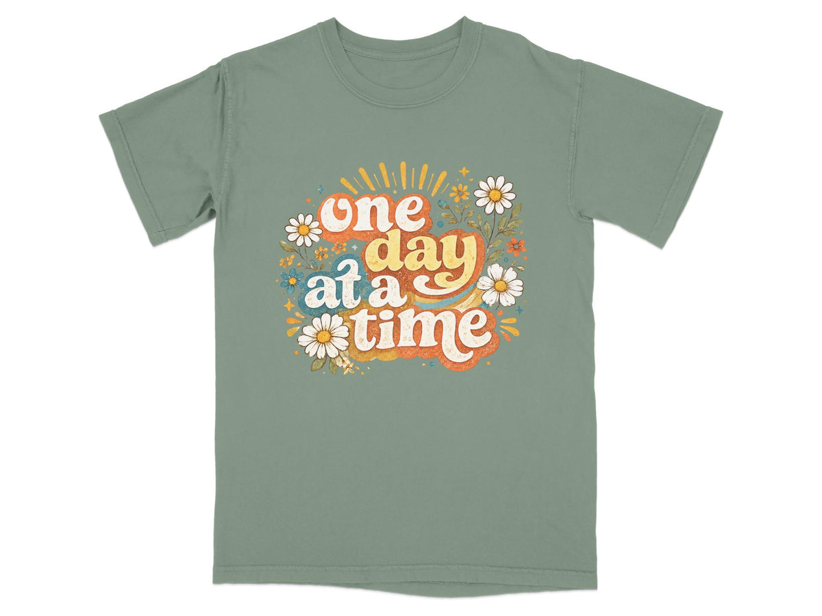 Green t-shirt with "one day at a time" text and floral graphics.
