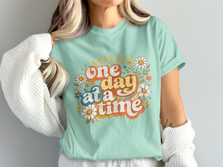 T-shirt with "one day at a time" text and floral graphics.