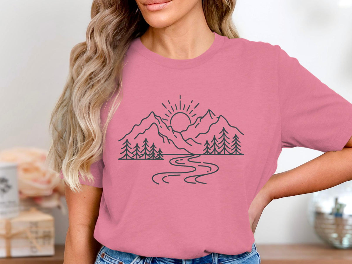 Pink t-shirt with black line art of mountains, sun, trees, and a river.