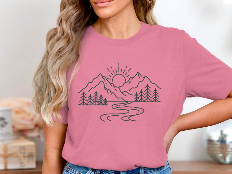 Pink t-shirt with black line art of mountains, sun, trees, and a river.