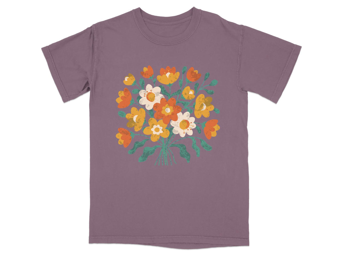 Purple t-shirt with a bouquet of orange, yellow, and white flowers.