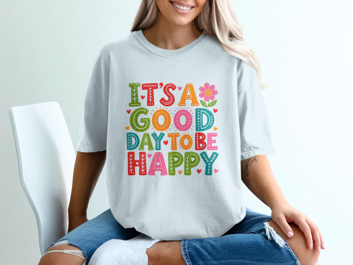 White t-shirt with colorful "It's A Good Day To Be Happy" text and flower design.