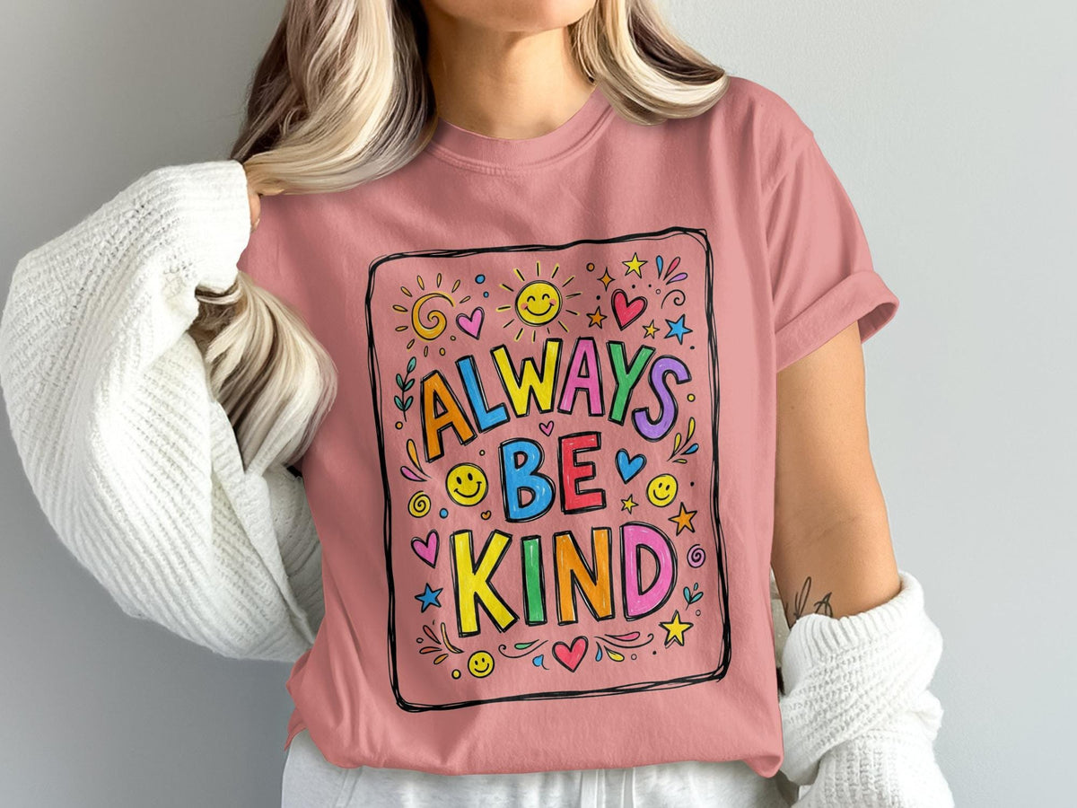 Pink t-shirt with "Always Be Kind" slogan surrounded by colorful illustrations.