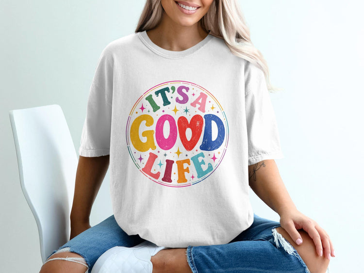 White t-shirt with "IT'S A GOOD LIFE" text graphic in a colorful, distressed circular design.