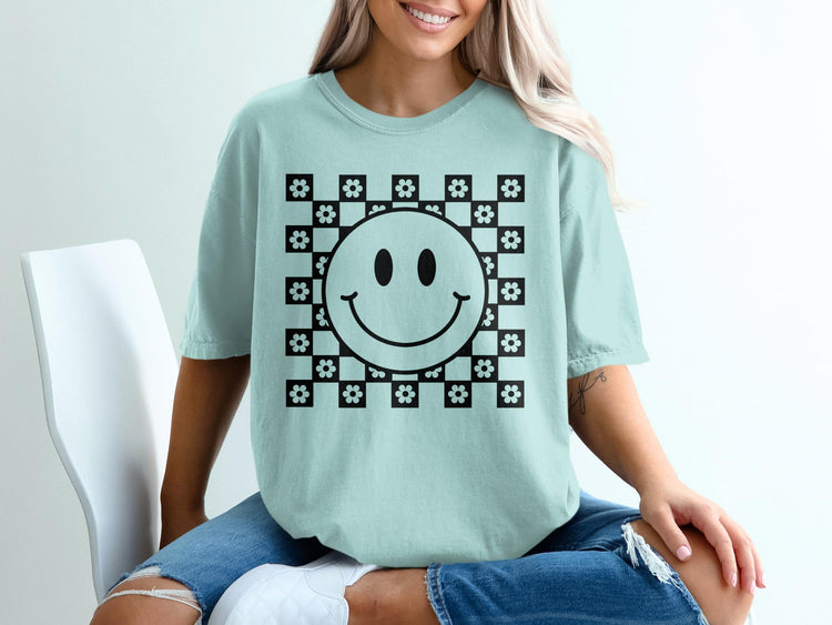 Light blue t-shirt with black smiley face and floral checkerboard pattern.