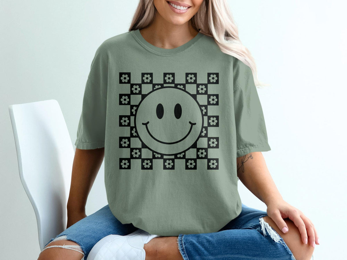 Green t-shirt with black smiley face and floral checkerboard graphic.
