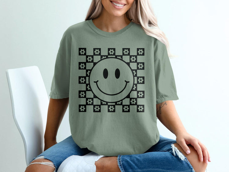 Green t-shirt with black smiley face and floral checkerboard graphic.