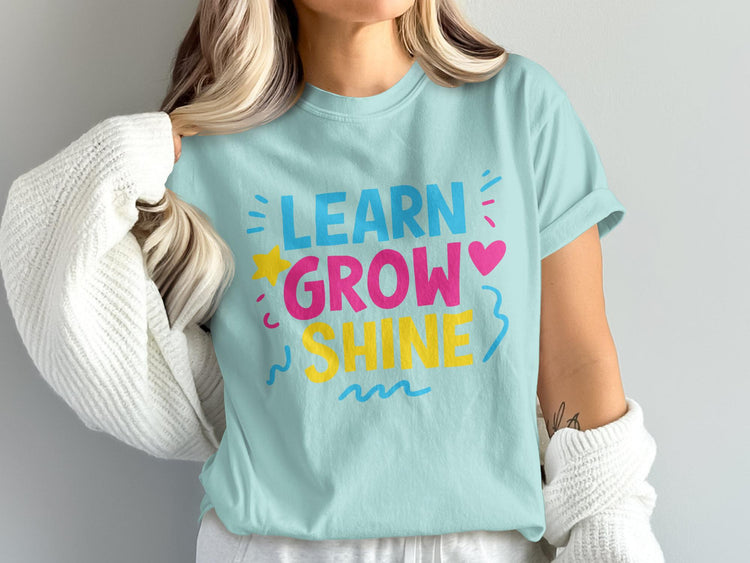 Light blue t-shirt with "LEARN GROW SHINE" in colorful block letters.