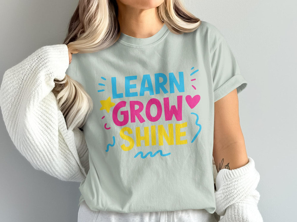Light blue t-shirt with "LEARN GROW SHINE" graphic in pink, blue, and yellow.