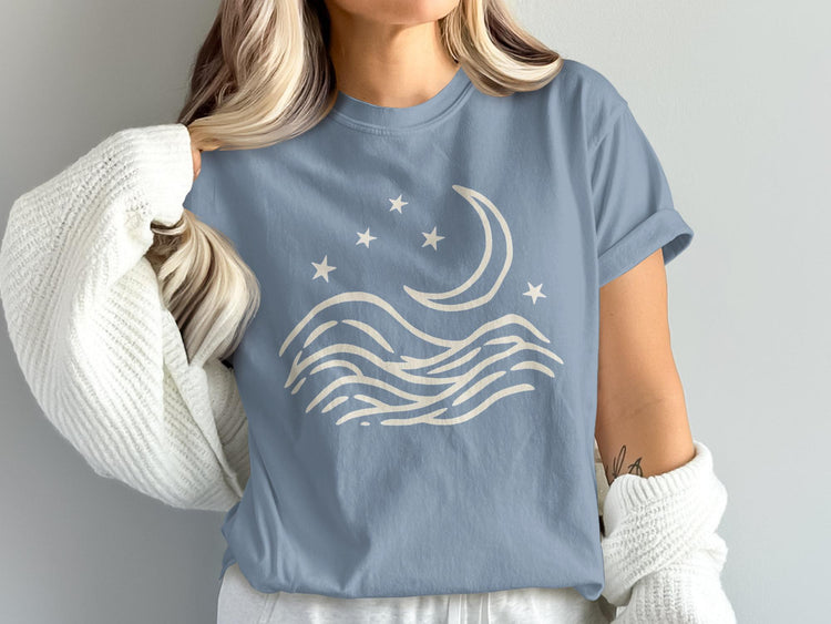Blue t-shirt with a cream crescent moon, stars, and wavy lines graphic.