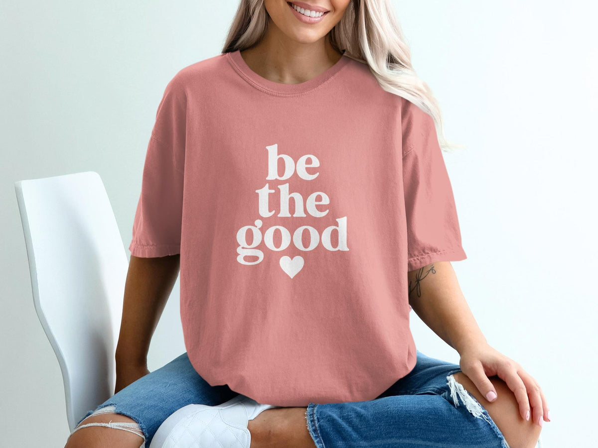 Pink t-shirt with white text "be the good" and a heart.