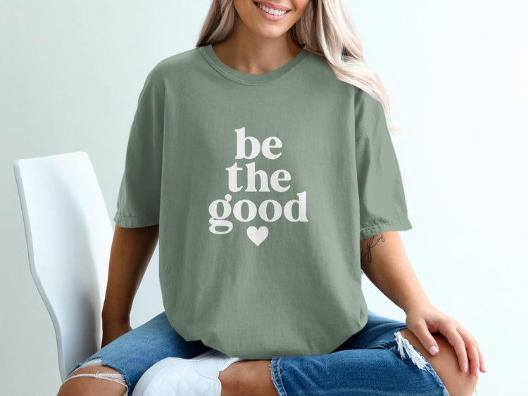 Sage green t-shirt with white text "be the good" and a heart.