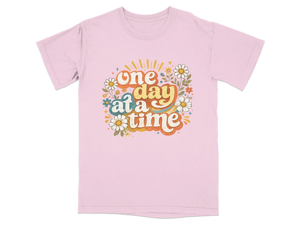 Pink t-shirt with "one day at a time" text and floral graphic.