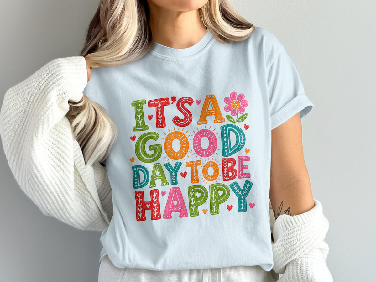 Light blue t-shirt with colorful text "It's a Good Day to Be Happy" and decorative elements.
