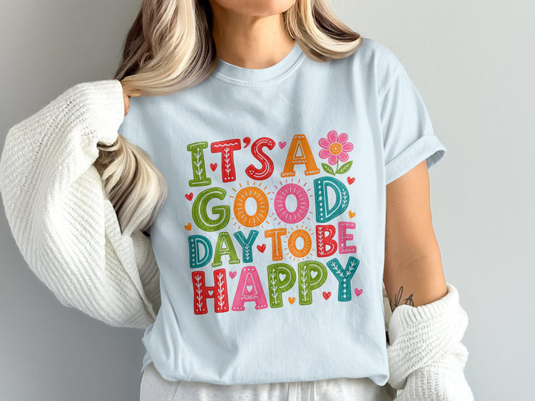 Light blue t-shirt with colorful text "It's a Good Day to Be Happy" and decorative elements.