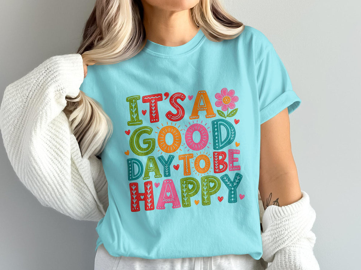 Light blue t-shirt with "It's a good day to be happy" text and floral designs.