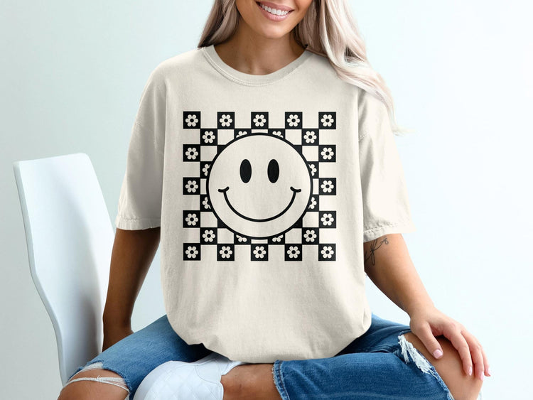 T-shirt with a black and white checkerboard pattern featuring a smiley face and flowers.