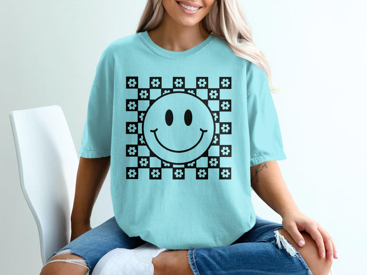 Light blue t-shirt with a black checkerboard pattern and smiley face with flowers.
