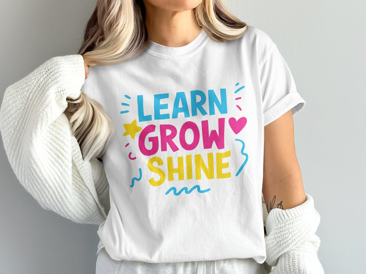 White t-shirt with "LEARN GROW SHINE" in colorful text and playful graphics.