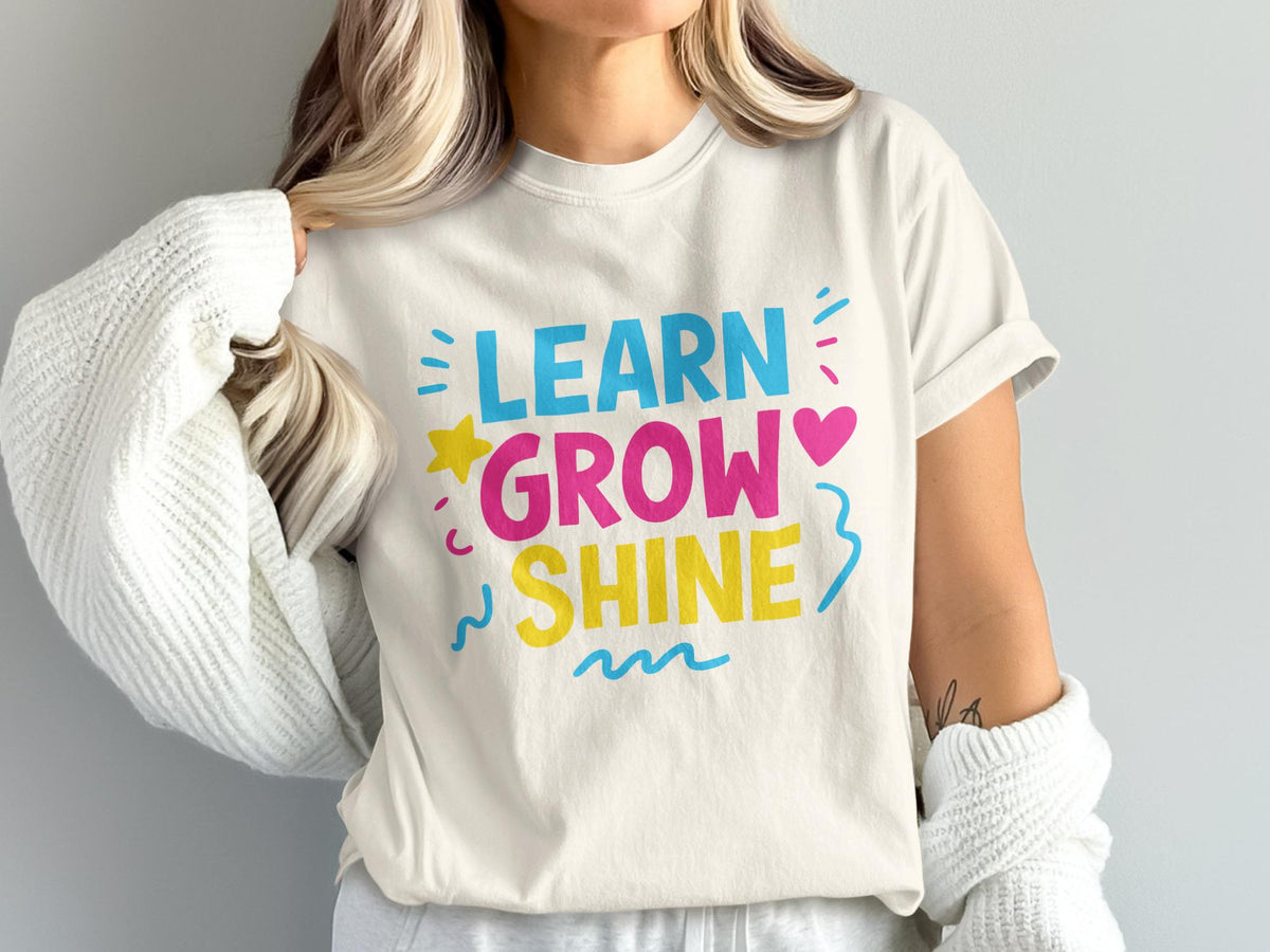 Cream t-shirt with "LEARN GROW SHINE" text in blue, pink, and yellow.