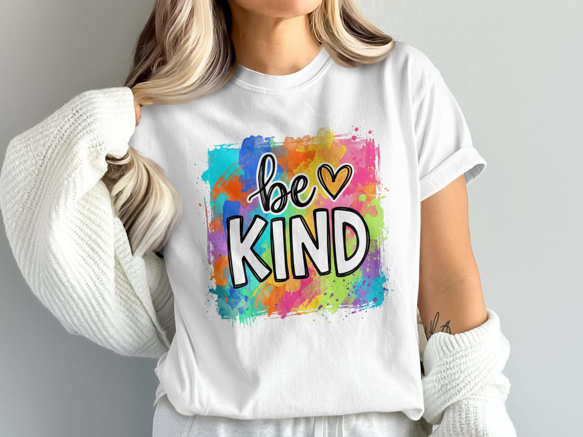 White t-shirt with "be KIND" text on colorful watercolor background.