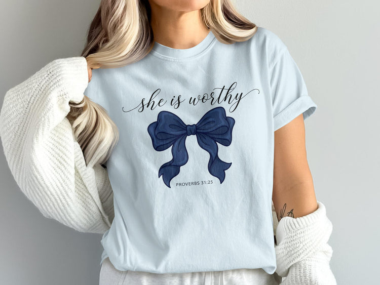 Light blue t-shirt with "she is worthy" and blue bow, PROVERBS 31:25.