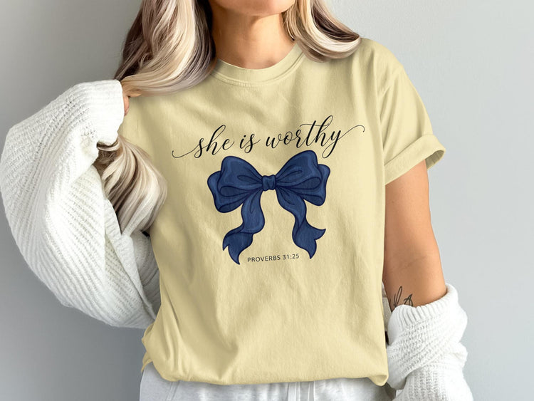 Cream t-shirt with dark blue bow graphic and text "she is worthy PROVERBS 31:25".